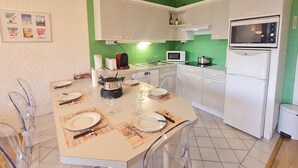 Eine kompakte Küche mit weißen Schränken, einer Mikrowelle, einem Herd und einem Kühlschrank.