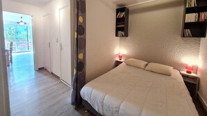 A bedroom with a bed, bedside lamps, a bookshelf, and a door leading to a balcony.