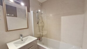 A bathroom with a white sink, mirror, and glass-enclosed shower.