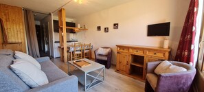 A living room with a sofa, a coffee table, a TV, and a wooden cabinet. - Studio 4 ppl, balcony mountain view (Les Deux Alpes)