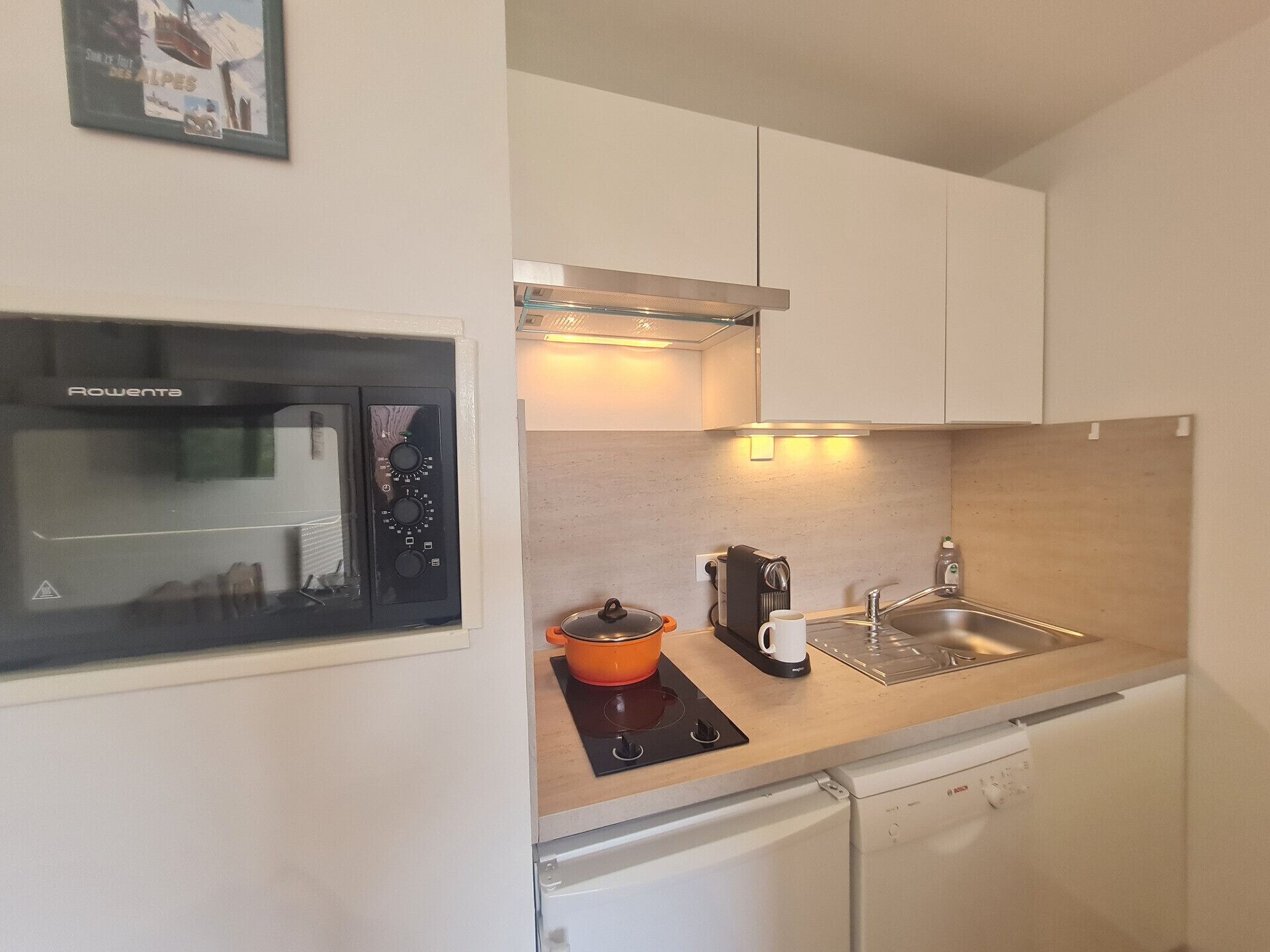 A compact kitchen with a built-in oven, a coffee maker, and a sink.