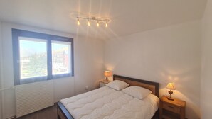 Ein Schlafzimmer mit einem Bett, zwei Nachttischlampen, einem Fenster und einer Heizung.