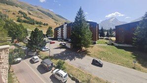 Ein Parkplatz mit mehreren Autos, ein Gebäude im modernen Stil und eine gebirgige Landschaft im Hintergrund.