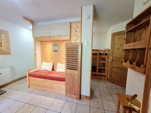 Une pièce confortable avec un lit en bois, une petite table et une armoire en bois.