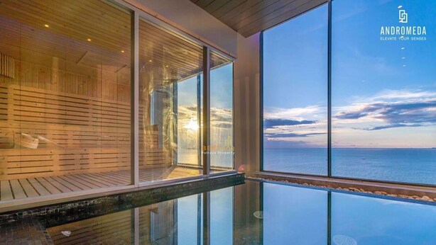 A modern infinity pool with a glass edge, wooden deck, and a view of the sea. - High end condo in popular area with an amazing sea view, 2 min from the beach (Bang Lamung)