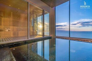 A modern infinity pool with a glass edge, wooden deck, and a view of the sea. - High end condo in popular area with an amazing sea view, 2 min from the beach (Bang Lamung)