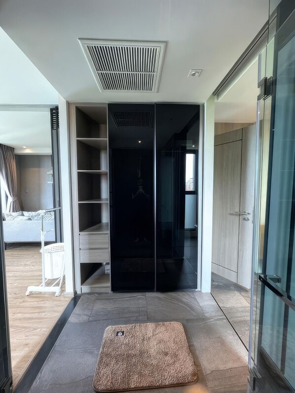 Un intérieur moderne avec une porte sombre au centre, un petit tapis et un placard visible.