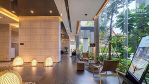 A modern lobby with a wooden wall, seating area, and a glass wall with plants. - High end condo in popular area with an amazing sea view, 2 min from the beach (Bang Lamung)