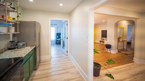 Una cocina moderna con refrigerador, una encimera con electrodomésticos y un pasillo que conduce a un comedor.