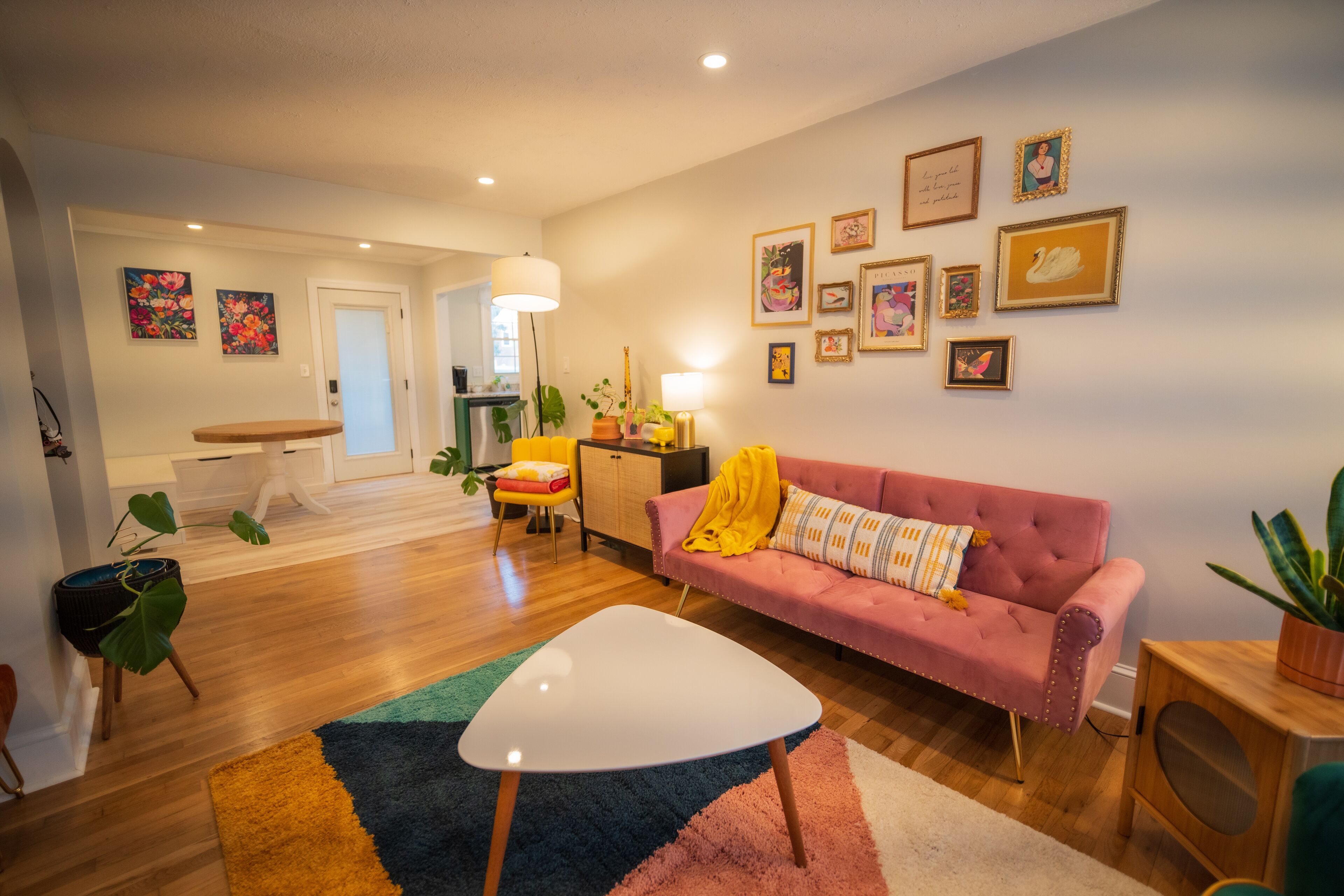 A modern living room with a pink sofa, a white coffee table, and a colorful rug.