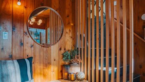 A wooden interior with a bench, a mirror, a plant, and a staircase. - Lightfoot Cabin (Running Springs)