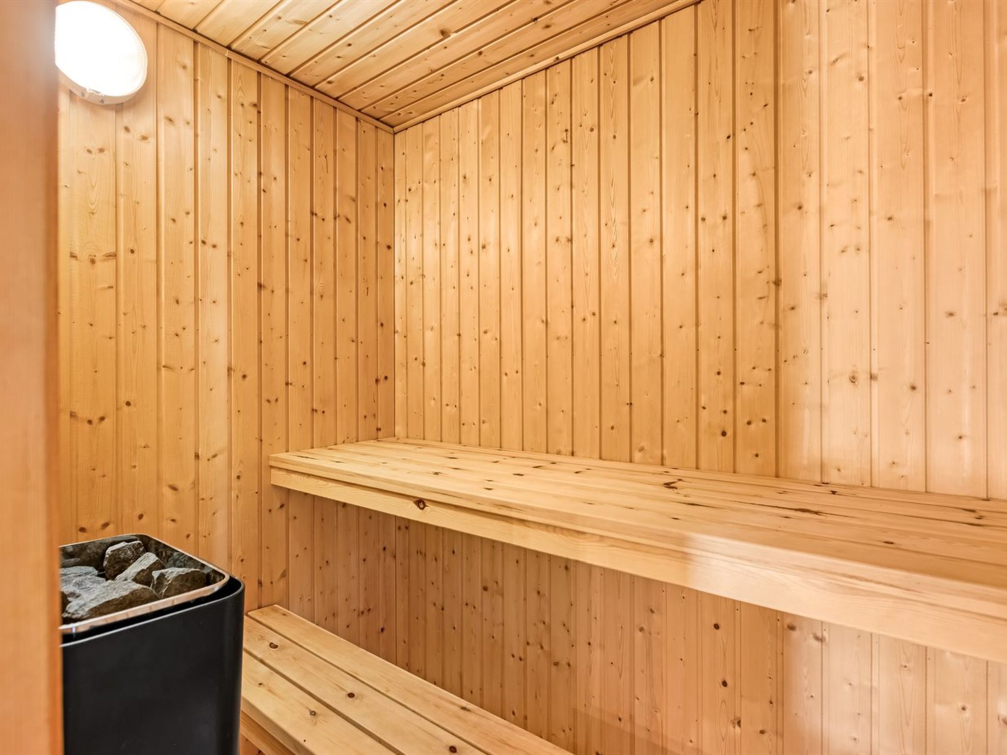 Un sauna avec des murs en bois et un banc.