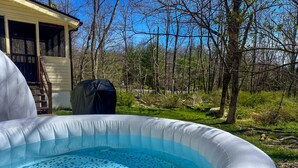An inflatable pool in a backyard with a wooden deck and a covered grill.