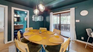 A dining area with a round table, chairs, and pendant lights.