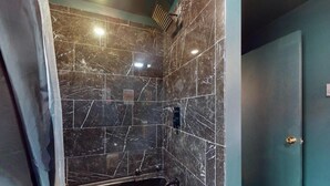 Un baño con ducha, lavamanos y puerta.