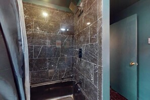Een badkamer met een douche, wastafel en deur.