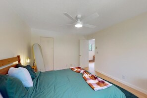 Une chambre à coucher avec un lit, un ventilateur de plafond et une porte donnant sur une autre pièce.