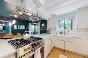 Een moderne keuken met witte kastjes, een roestvrijstalen fornuis en een groot raam voor natuurlijk licht.