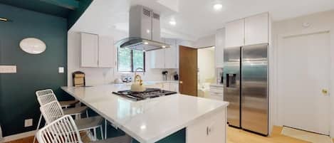 A modern kitchen with white cabinetry, a stainless steel refrigerator, and a central island with seating.