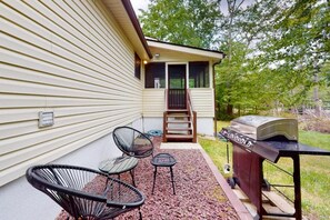 Une terrasse avec des meubles d’extérieur, un barbecue et une maison dotée d’un porche abrité.