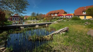 Een woonwijk met huizen, een klein vijvertje en een houten brug.