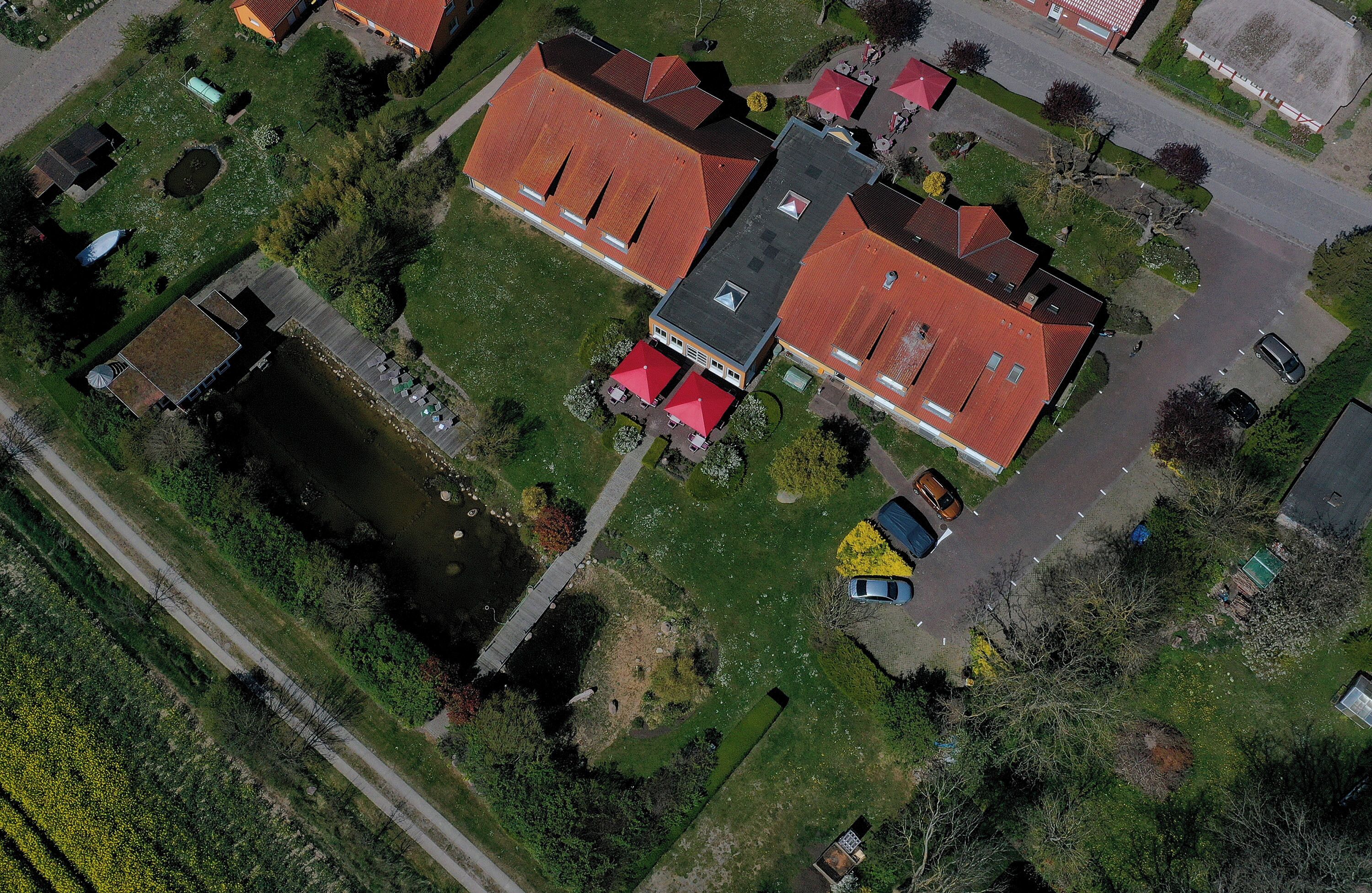 An aerial view of a residential area with houses, a pond, and a road.