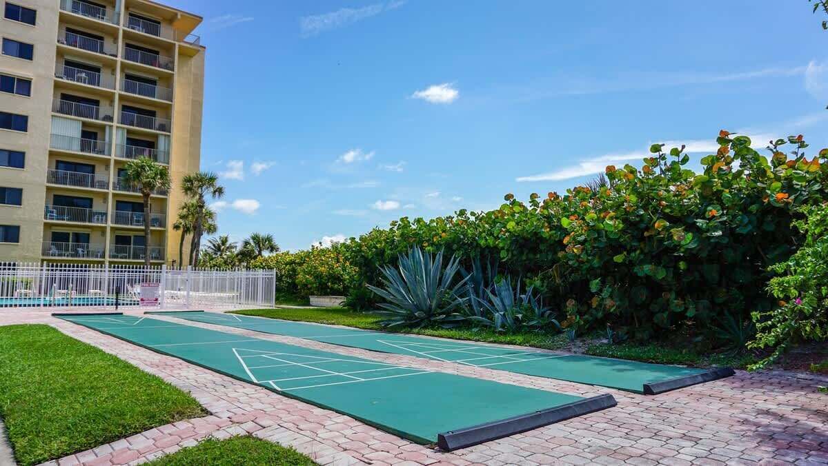 A courtyard with a shuffleboard court, a pool, and a building with balconies.