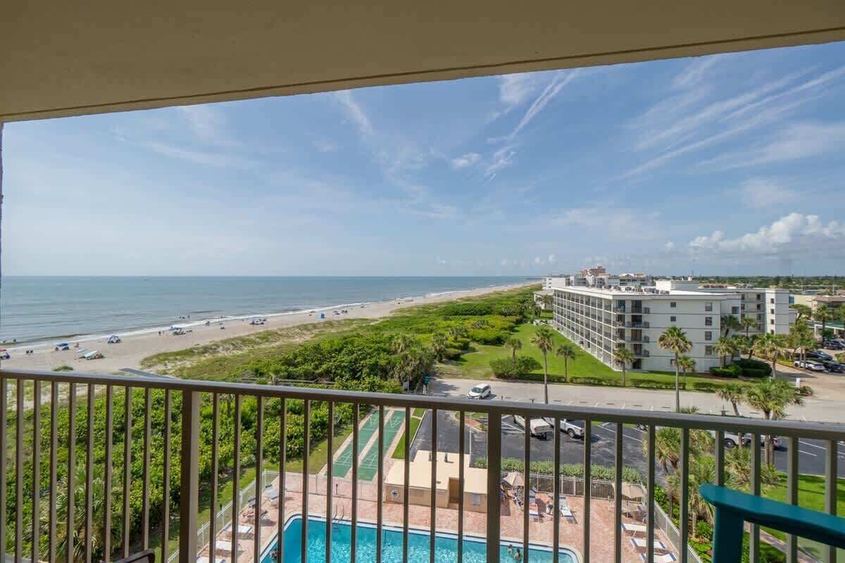A hotel with a pool, beach view, and a tennis court.