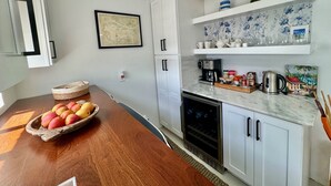 A kitchen with white cabinets, a marble countertop, a coffee maker, and a wine cooler. - Exquisite Waterfront Villa (Jolly Harbour)