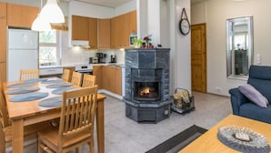 Una cocina moderna con armarios de madera, una chimenea central y una zona de comedor con mesa y sillas.