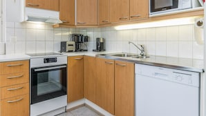 Una cocina moderna con armarios de madera, horno empotrado, microondas, cafetera y lavavajillas.