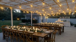 An outdoor dining area with wooden tables and chairs, string lights, and candles. - Luxury Lakeview Home w/ Pool | Perfect for Events (dade city)