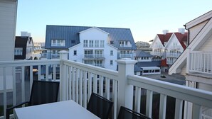 Un quartier résidentiel avec plusieurs maisons, un balcon agrémenté d’une table et de chaises, et un ciel dégagé.