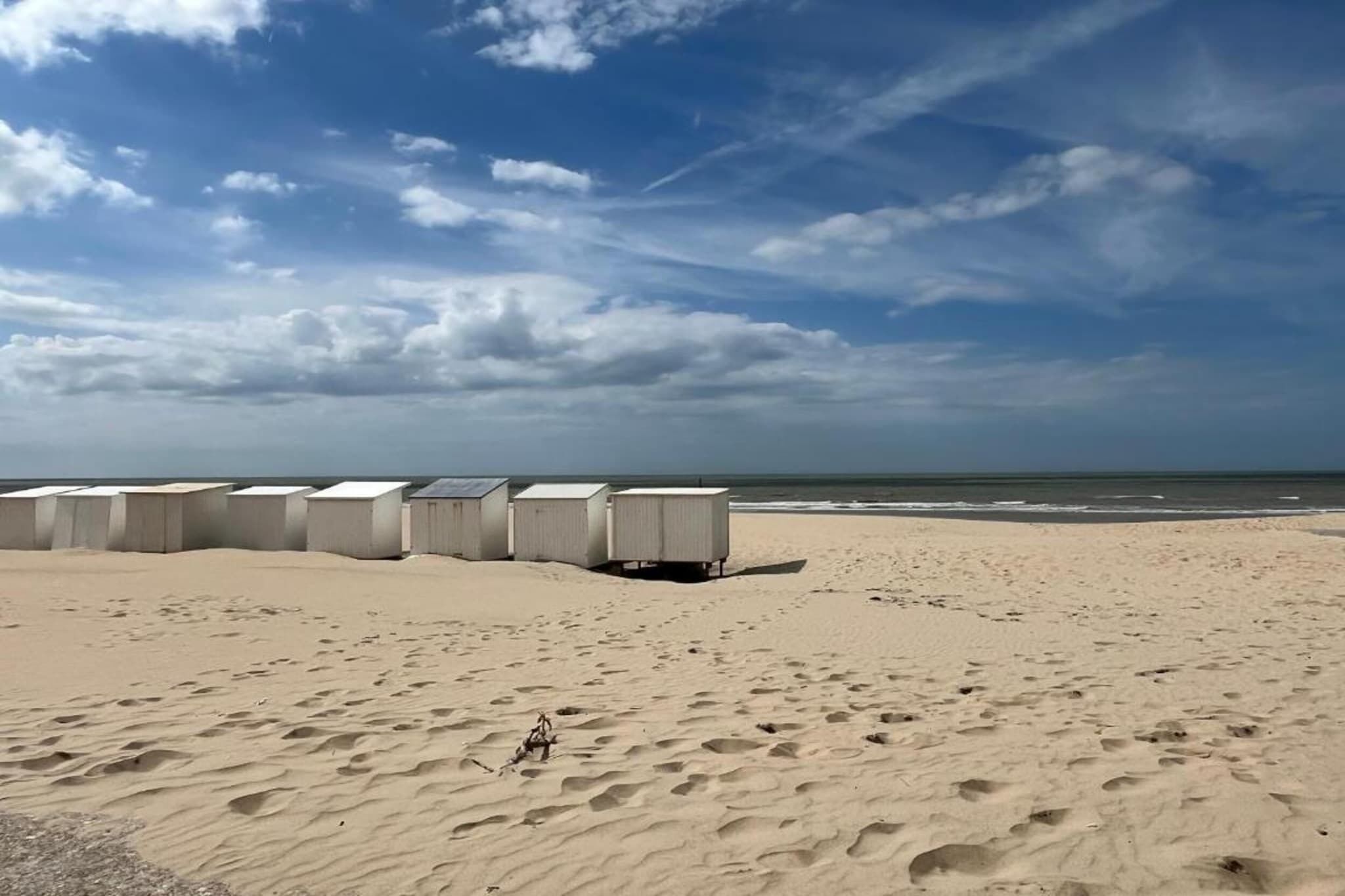 Una playa con varias cabañas blancas alineadas.