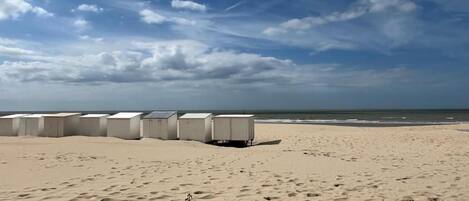 Una playa con varias cabañas blancas alineadas.