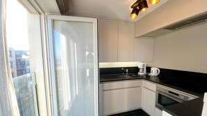A modern kitchen with a black countertop, stainless steel appliances, and a sliding glass door leading to a balcony. - Apartment in Nieuwpoort near the Beach (Nieuwpoort)