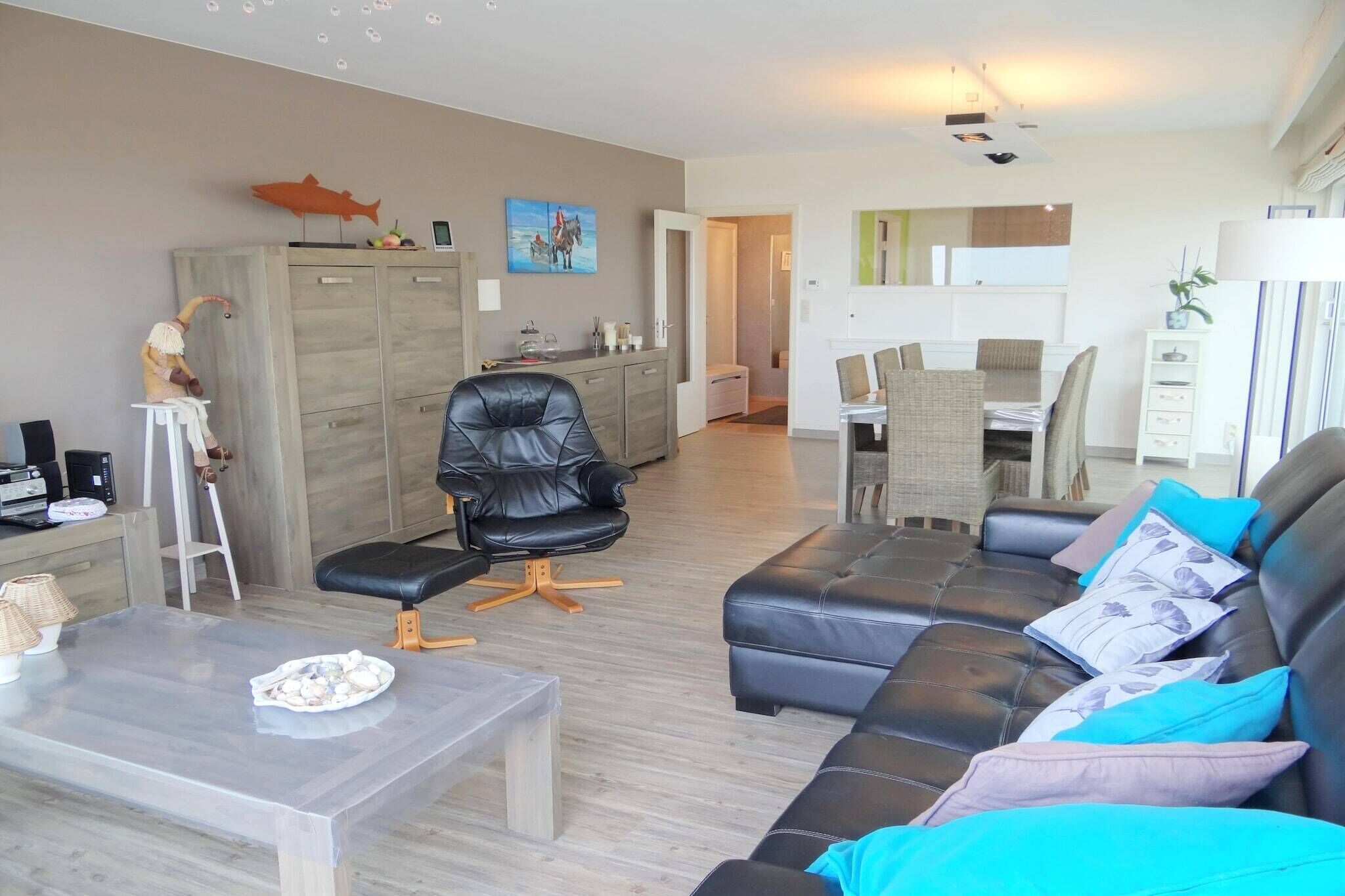 A modern living room with a leather sofa, a glass coffee table, and a dining area with a table and chairs.