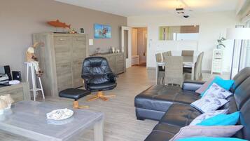 A modern living room with a leather sofa, a glass coffee table, and a dining area with a table and chairs.