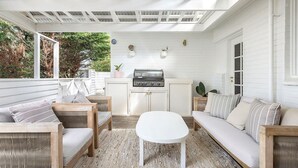 A covered patio with a grill, seating area, and a view of the outdoors. - Long Island Beach Getaway (Frankston)