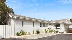 A single-story white house with a tiled roof, a garage, and a small front yard with cacti. - Long Island Beach Getaway (Frankston)