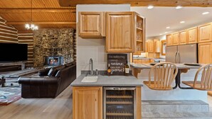 Une cuisine moderne avec des meubles en bois, un réfrigérateur à vin encastré et un mur en pierre.