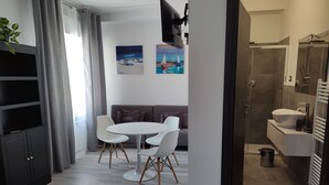 Et moderne hotelværelse med spiseplads, sofa og bruser.