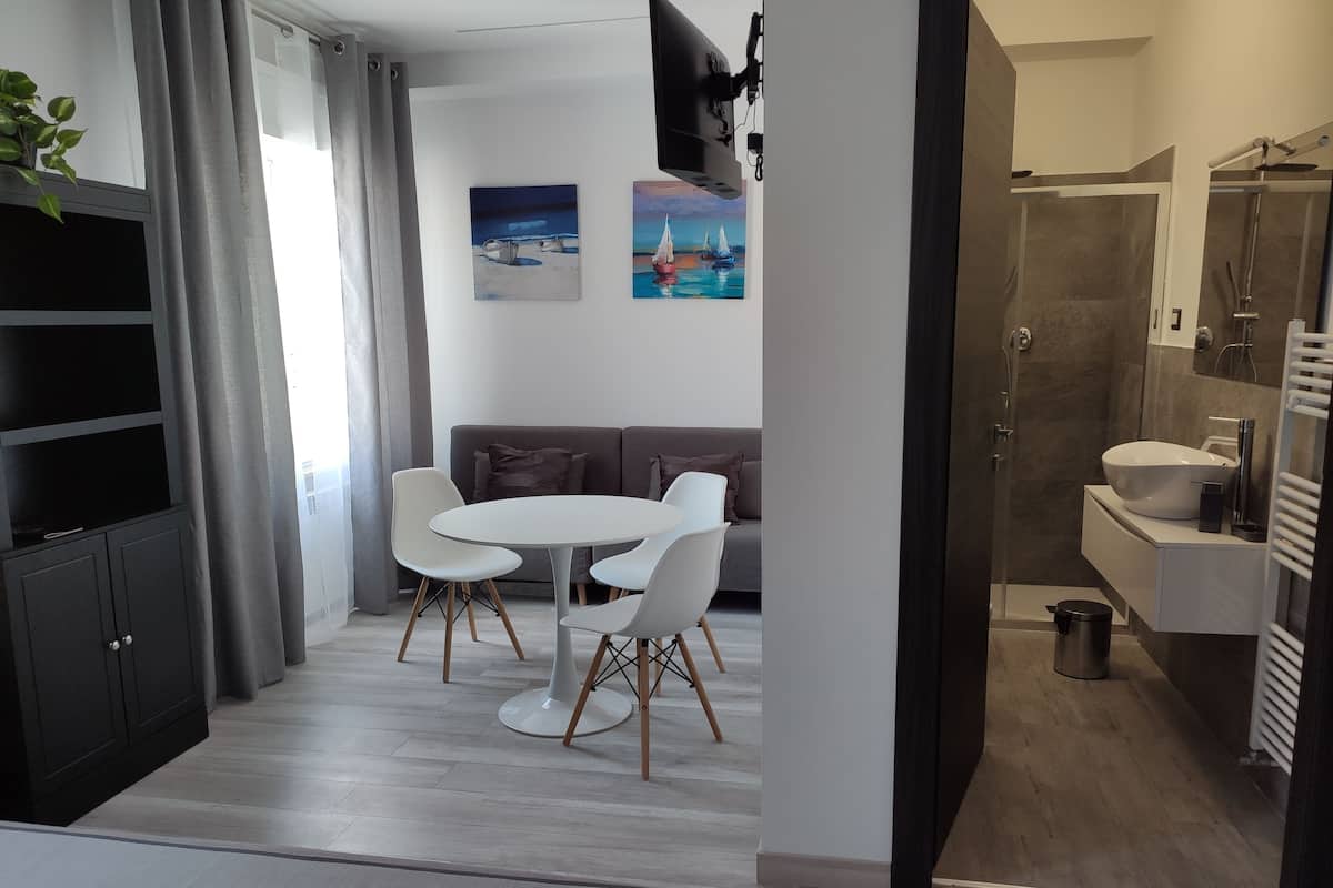 A modern hotel room with a dining area, a sofa, and a shower.