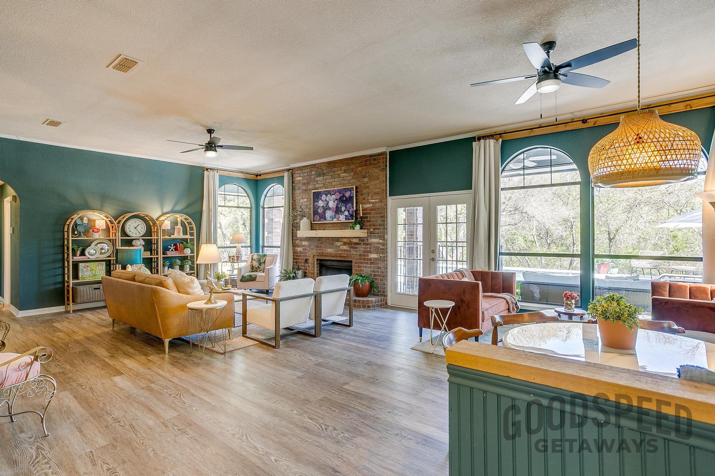 A spacious living room with hardwood flooring, a fireplace, and large windows.