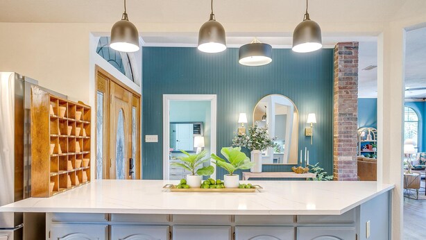 Una cocina con una isla grande, armarios de madera y una pared de ladrillo decorativa.