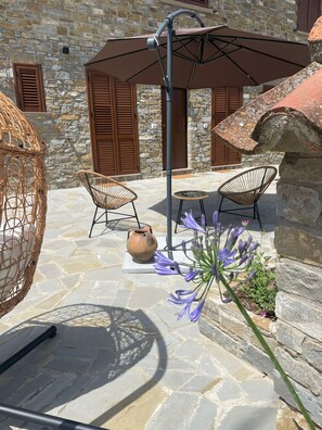 An outdoor seating area with wicker chairs, a table, and a large umbrella. - CASALE CONTI (Castellabate)