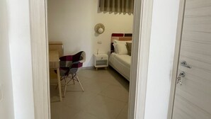 A hotel room with a bed, a nightstand, a chair, and a window with curtains. - CASALE CONTI (Castellabate)