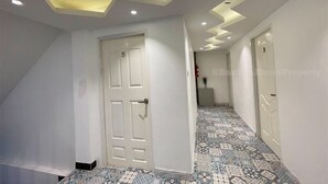 Un passadís amb sòls estampats, parets blanques i portes numerades amb els números 5 i 3.