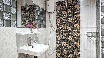 Une salle de bain avec un lavabo blanc, une douchette à main et des carreaux décoratifs.