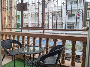 A balcony with a wrought iron railing, two wicker chairs, and a small round table. - YOK Guesthouse Jomtien (Pattaya)